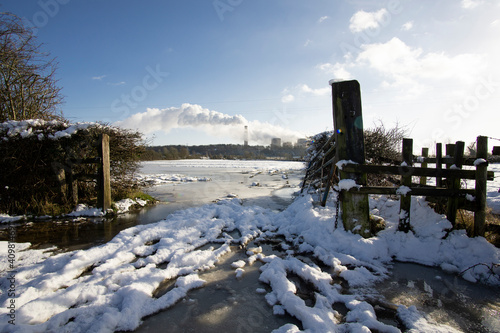 Muddy entrance to flooded field frozen in winter