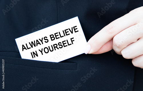 A businessman puts in his pocket a business card with the text Always believe in yourself.