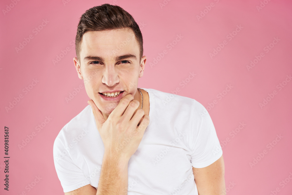 A man in a white t-shirt gestures with his hands emotions pink background studio cropped view A man in a white t-shirt gestures with his hands emotions pink background studio cropped view