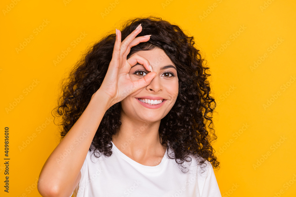 Photo portrait of girl showing watching in okay sign approval smiling isolated on vibrant yellow color background Photo portrait of girl showing watching in okay sign approval smiling isolated on vibrant yellow color background