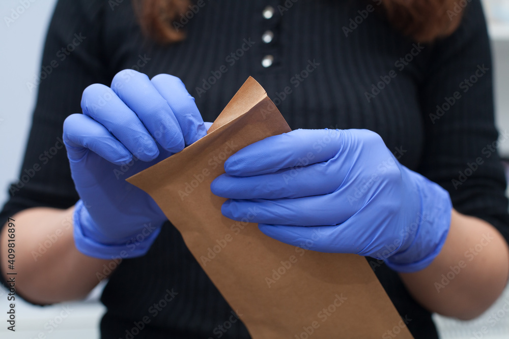 The master prints out tools for manicure. Sterile sealed disposable bag. Blue gloves..