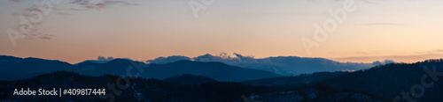 Panorama of the silhouette of mountains and forest on the background of sunset