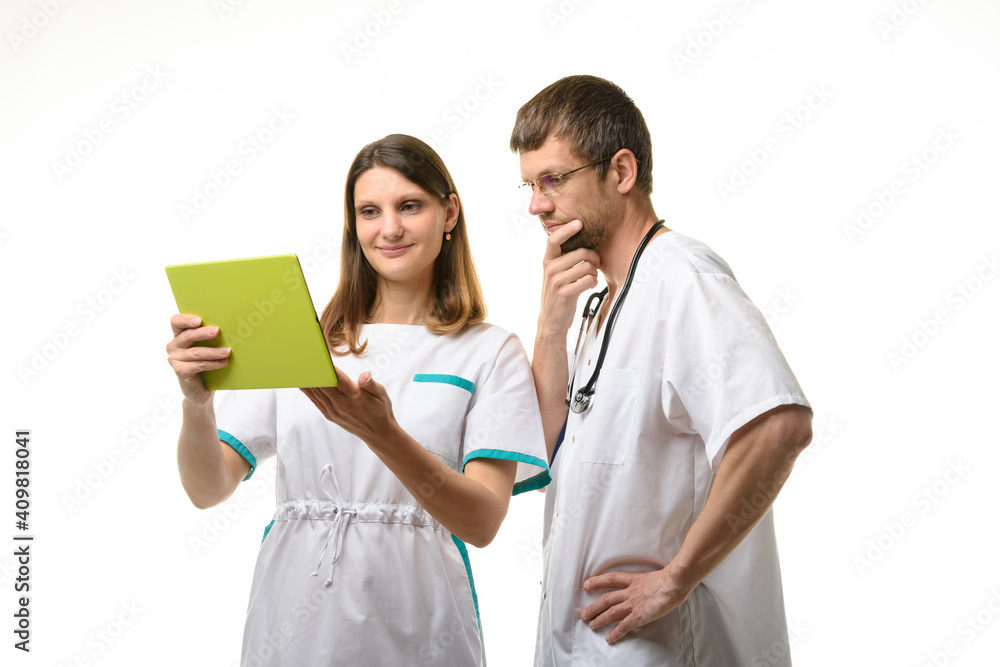The nurse shows the test results in a tablet computer, the doctor looks thoughtfully at the screen