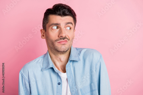 Photo of confused brunette handsome young man wear blue shirt isolated on pastel pink color background