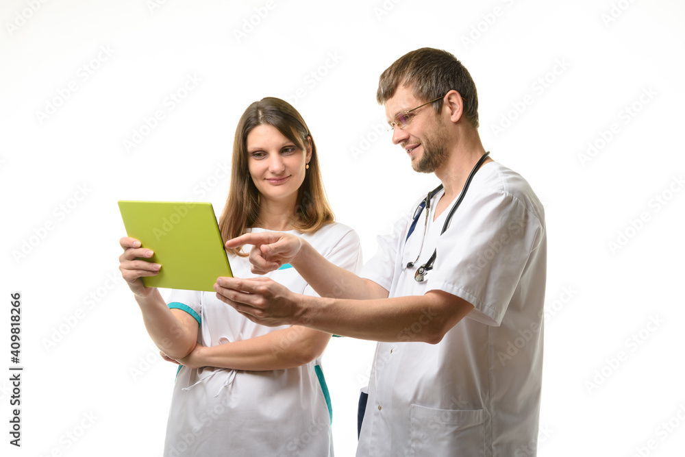 Two doctors discussing the patient's tests while looking at the tablet computer screen Two doctors discussing the patient's tests while looking at the tablet computer screen