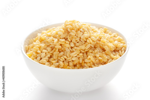 Crunchy Moong Dal in a white ceramic bowl, made with roasted Mung bean. Pile of Indian spicy snacks (Namkeen), under backlight, side view, against the white background.