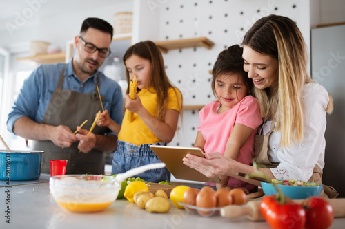 Overjoyed young family with kids having fun  cooking at home together