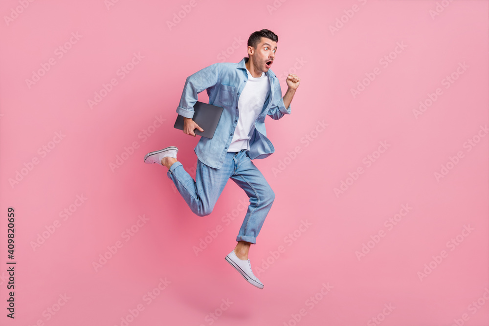 Full length body size view of nice motivated energetic guy jumping carrying laptop running fast isolated on pink pastel color background