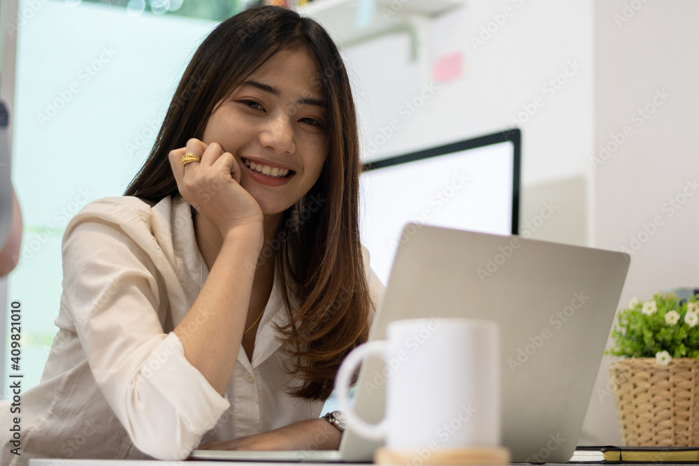 Young happy Asian businesswoman sitting in front of laptop computer and smiling. Young happy Asian businesswoman sitting in front of laptop computer and smiling.