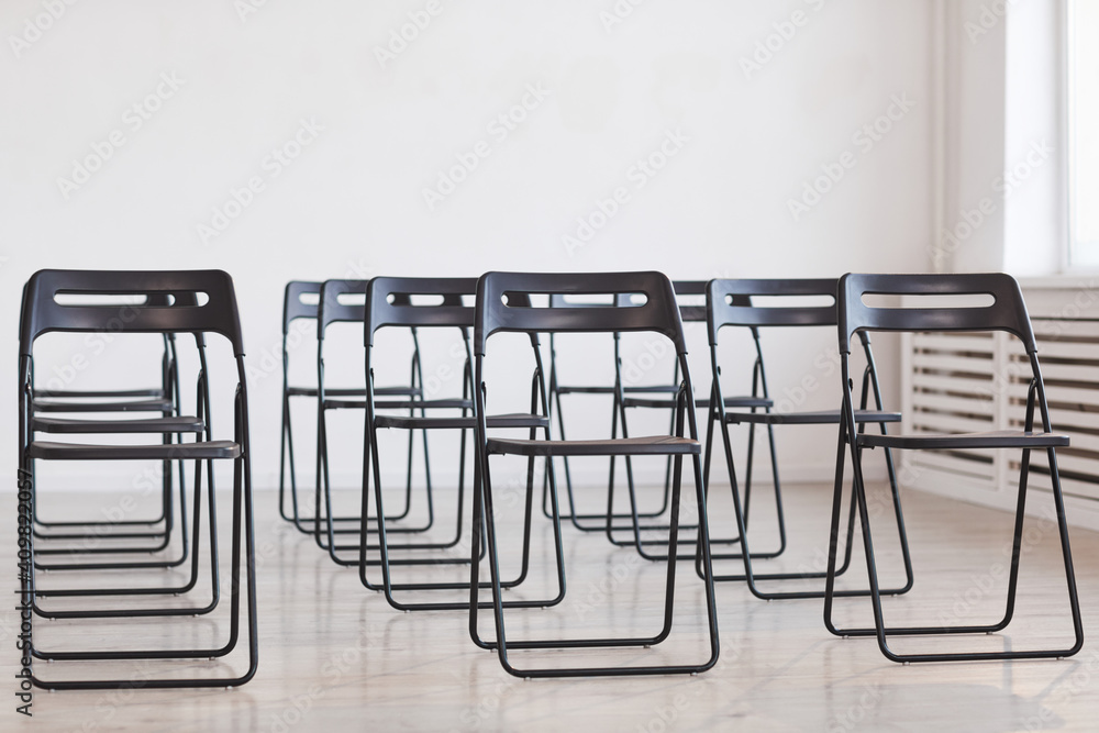 Full length background image of black metal chairs against white background set up for audience at business conference, copy space Full length background image of black metal chairs against white background set up for audience at business conference, copy space