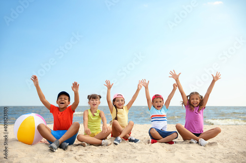 Sticker Group of happy children sitting on sand at sea beach. Summer camp