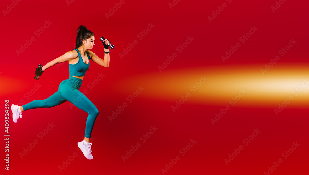 Banner,long format. A girl running in sportswear and with dumbbells in her hands on a red background with an empty side space for advertising.