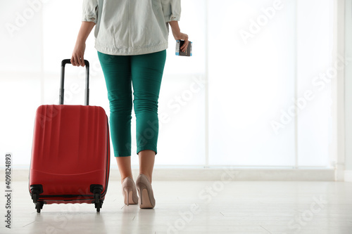 Businesswoman with red travel suitcase in airport. Space for text