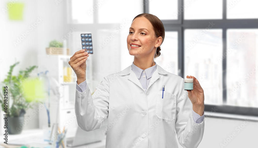 medicine, profession and healthcare concept - happy smiling female doctor comparing pills in jar and pack over medical office at hospital on background medicine, profession and healthcare concept - happy smiling female doctor comparing pills in jar and pack over medical office at hospital on background