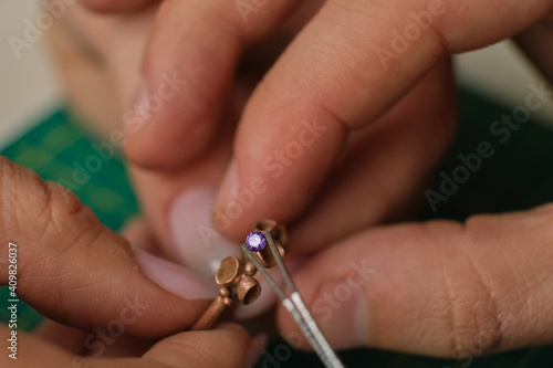 Macro shot. Craft jewelery making. Ring repairing. Putting the diamond on the ring. Desktop for craft jewellery making with professional tools. photo