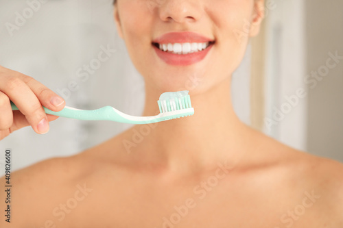 Woman holding toothbrush with paste indoors  closeup