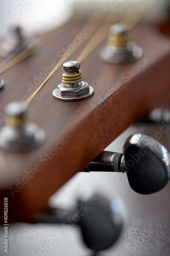 music and musical instruments concept - close up of acoustic guitar head with pegs