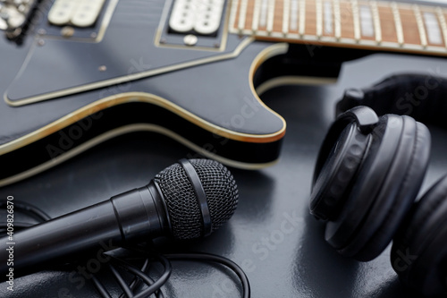 leisure, music and musical instruments concept - close up of bass guitar, microphone and headphones on black table