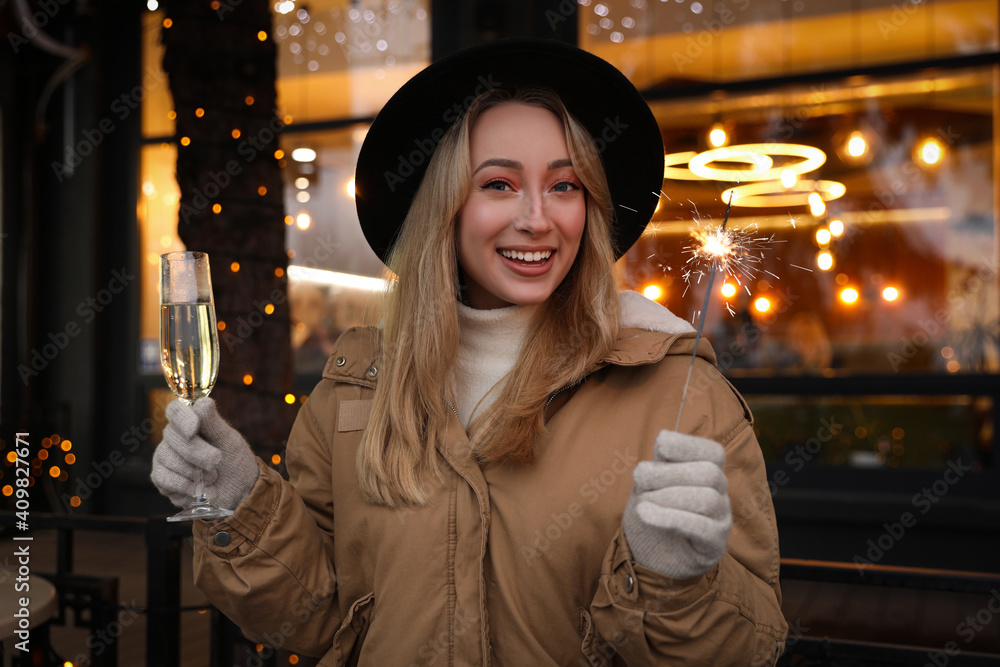Happy young woman with sparkler and glass of champagne at winter fair Happy young woman with sparkler and glass of champagne at winter fair