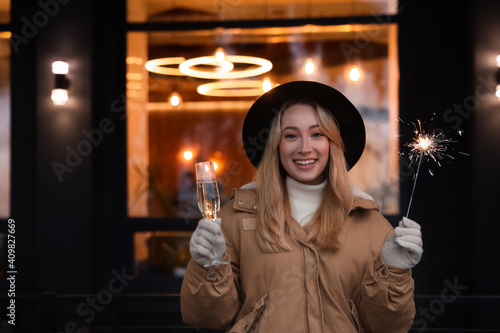 Happy young woman with sparkler and glass of champagne at winter fair