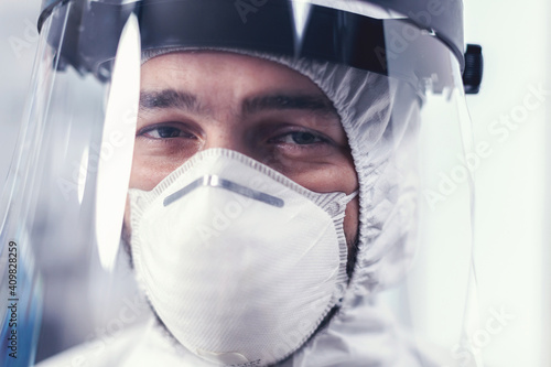 Close up of wear out medical engineer wearing face mask and ppe suit. Overworked researcher dressed in protective suit against invection with coronavirus during global epidemic. photo