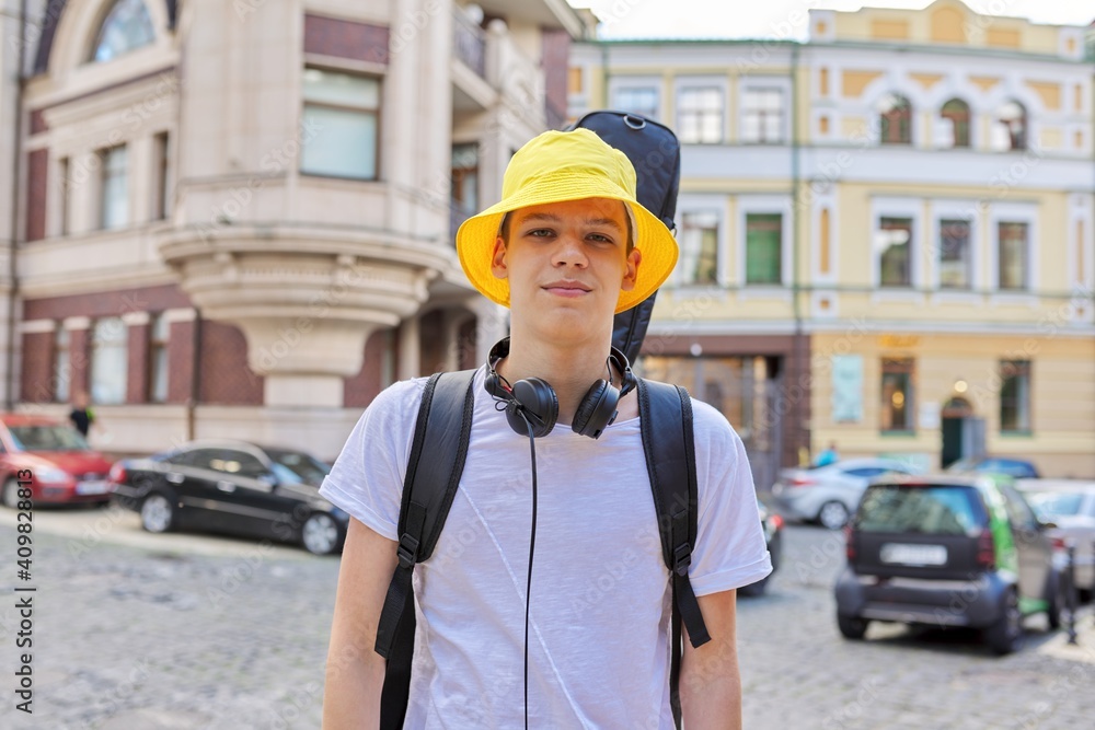 Portrait of creative handsome guy in yellow panama hat with guitar in case Portrait of creative handsome guy in yellow panama hat with guitar in case