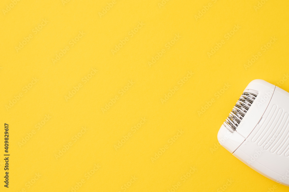 Compact electric epilator on yellow background. Free space for text. Compact electric epilator on yellow background. Free space for text.
