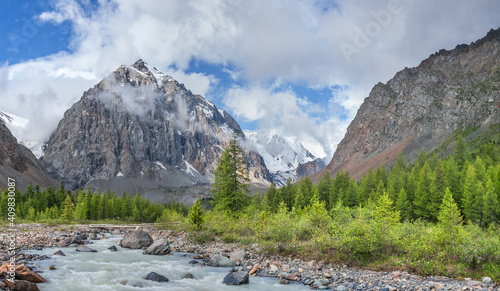 Mountain river flows into the gorge, cloudy morning