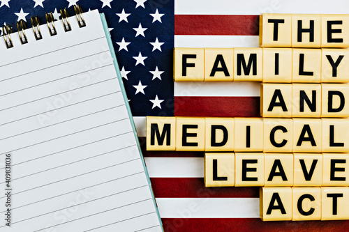 topview photo on FMLA (the family medical leave act) theme.  photo of open notepad with blank space, on a background of United States flag photo