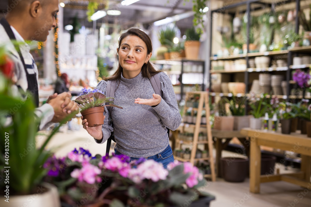 Female buyer consults with seller on how to choose geranium flowers in a flower shop