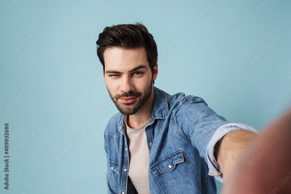 Young handsome pleased man winking while taking selfie photo Young handsome pleased man winking while taking selfie photo