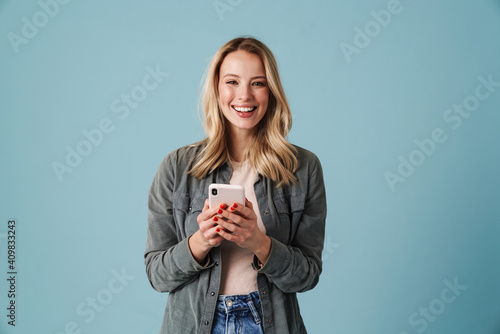 Fotografia Cheerful beautiful blonde girl smiling and using mobile phone