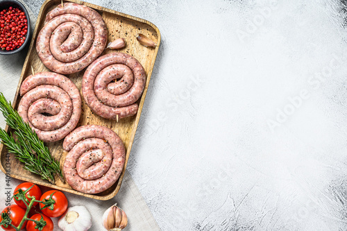 Raw German spiral sausages on a wooden tray. Gray background. Top view. Copy space