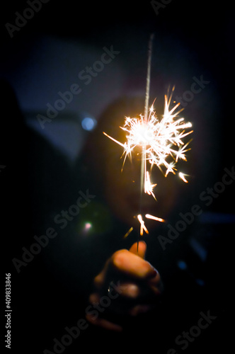 Female hand holding a burning sparkler in the night