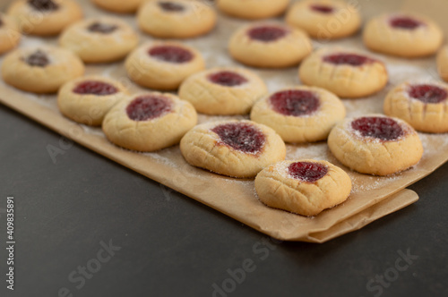 Blurred image of shortbread cookies on tracing paper on a black table.