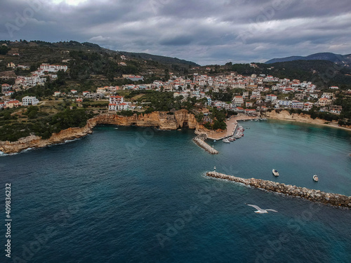 Aerial view over Votsi beach (Paralia Votsi) and the picturesque port with traditional wooden fishing boats in Alonnisos island during Winter period in Sporades, Greece © panosk18