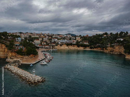 Aerial view over Votsi beach (Paralia Votsi) and the picturesque port with traditional wooden fishing boats in Alonnisos island during Winter period in Sporades, Greece