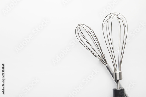 Close up of two silver whisks isolated on white background. Copy space.