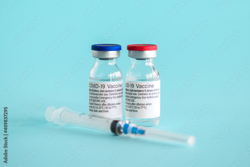 Ampoules with a vaccine against coronavirus infection COVID-19 and a syringe close-up on a light blue background Ampoules with a vaccine against coronavirus infection COVID-19 and a syringe close-up on a light blue background