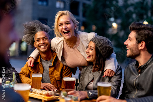 group of friends smiling and drinking at brewery  meeting of couple of millennials toasting with beers and eating fusion food  nightlife and social gathering of young people after covid19 outbreak