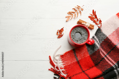 Flat lay composition with hot drink and warm plaid on white wooden table, space for text