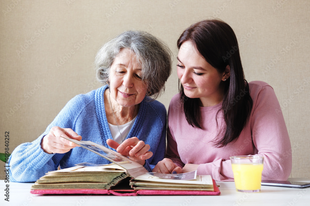 © sergign - Grandmother and daughter watching a family album with old photos together - Linking generations in a common activity - An elderly and a young woman talking together-Family relations concept © sergign - Grandmother and daughter watching a family album with old photos together - Linking generations in a common activity - An elderly and a young woman talking together-Family relations concept
