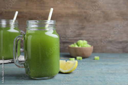 Fresh celery juice and lemon slice on blue wooden table, closeup. Space for text