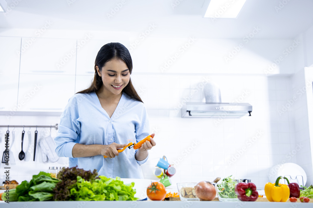 Woman is making fresh salad in the kitchen.