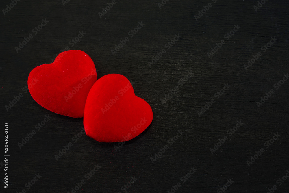 Fototapeta premium two red hearts on a black wooden background. Valentines Day concept. The 14th of February.