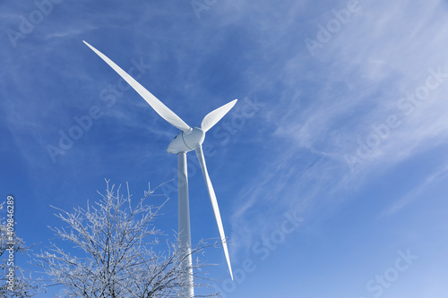 wind turbine on sky. Large wind turbine next to a tree with snow. Wind turbine in winter. Winter in East Frisia 