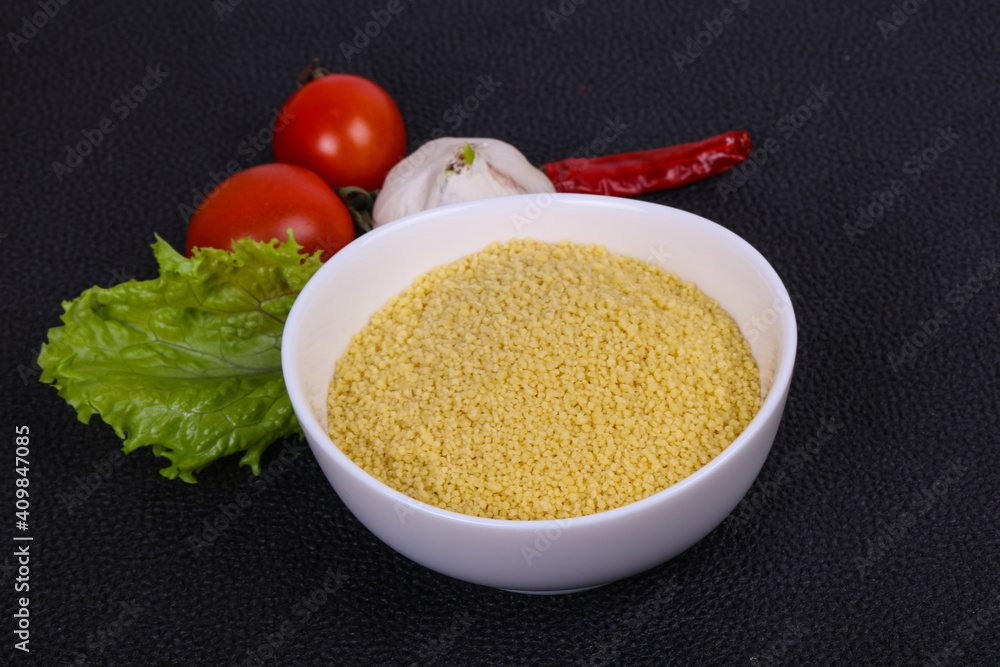 Raw couscous in the bowl served salad leaves, tomato and pepper Raw couscous in the bowl served salad leaves, tomato and pepper