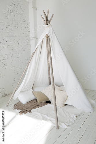 Spacious stylish modern trendy loft apartment in white and light colors. brick wall, wood floor, shelving, pallet bed and teepee-shaped children's house. everything is white with gray tints. © 4595886