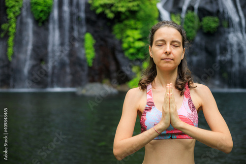 Close up of namaste mudra. Young woman meditating, practicing yoga and pranayama with namaste mudra near waterfall. Yoga outdoor concept. Copy space. Banyumala waterfall Wanagiri, Bali. photo