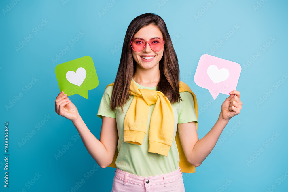 Photo of young lovely pretty attractive happy smiling girl in funky glasses hold heart icons isolated on blue color background - obrazy, fototapety, plakaty 